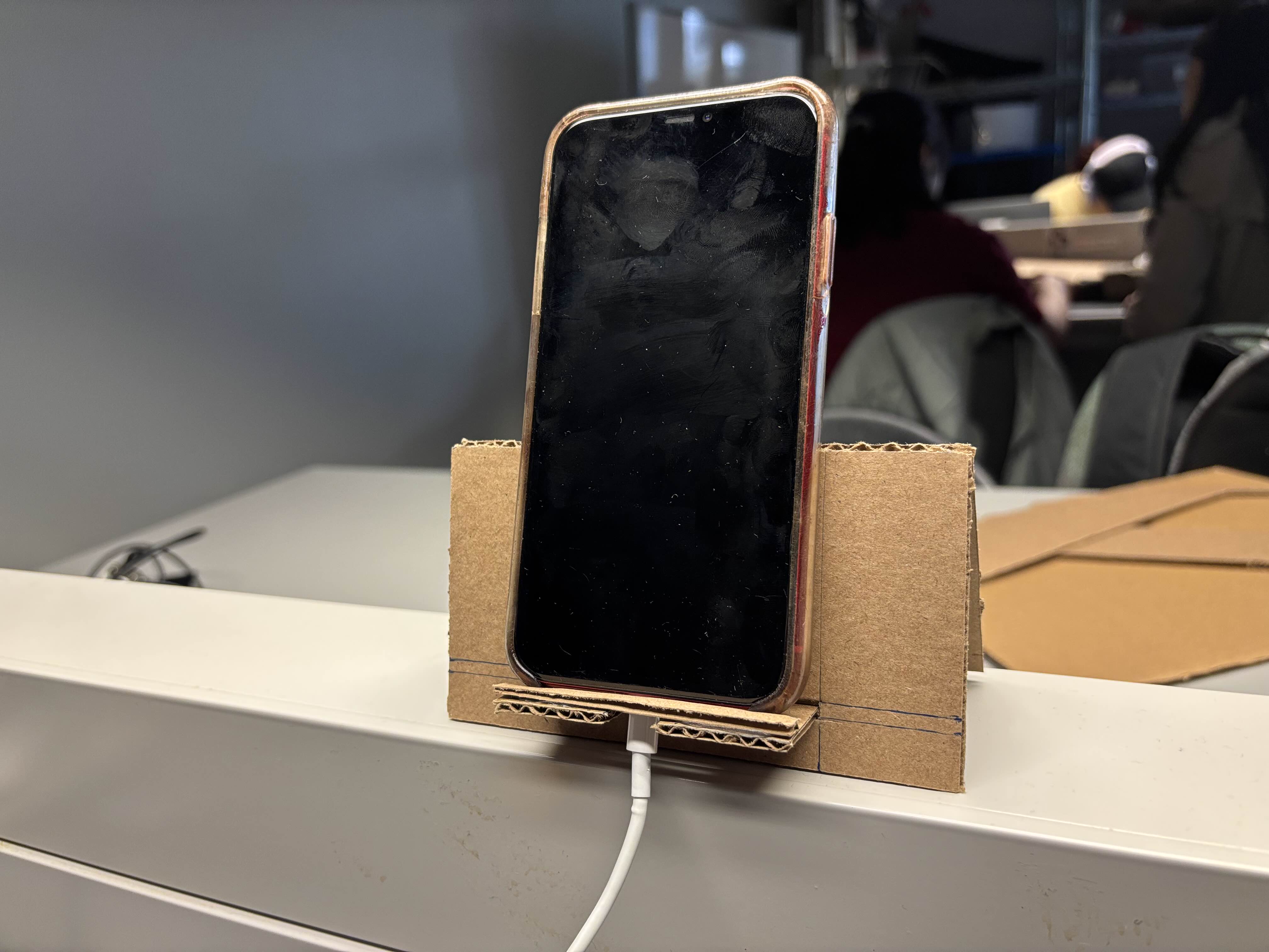 The changes I made to the design of the phone stand included creating a hole where a charger can fit through, and adding a ridge with extra cardboard that prevents the phone from slipping out of the stand.